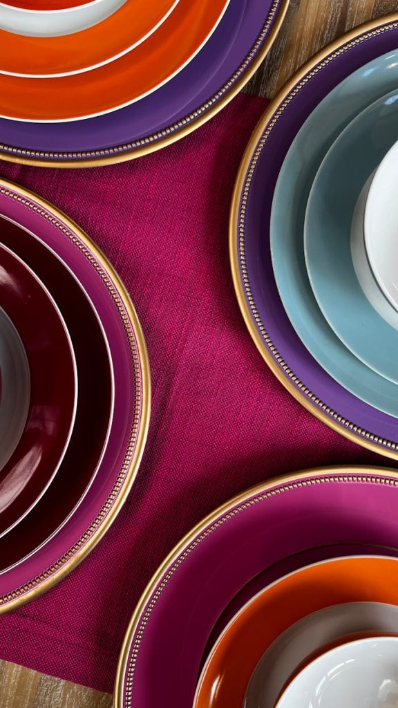 Top view of colorful ceramic plates on a vibrant pink tablecloth, showcasing elegance and style.